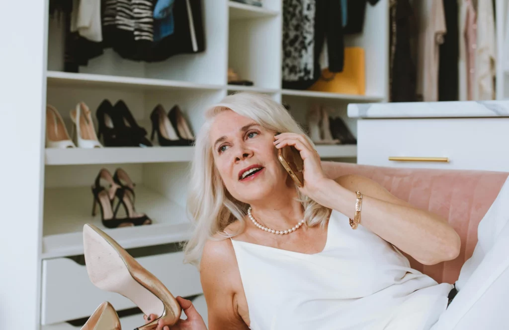 pexels-anastasia-shuraeva-5705513_optimized 1 - RenovSmart Femme souriante parlant au téléphone tout en tenant une chaussure dans un dressing organisé.