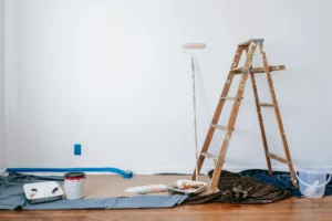 pexels-blue-bird-7218525_optimized - RenovSmart Matériel de peinture et échelle en bois utilisés pour rénover un mur blanc dans une pièce.