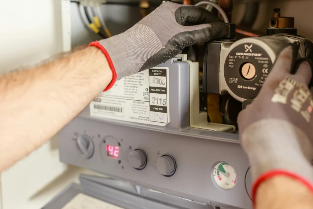 Technicien ajustant une pompe à chaleur avec gants de protection.