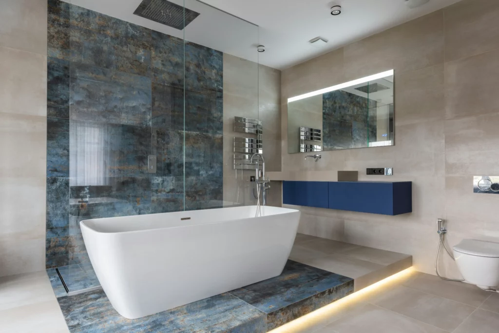 Salle de bain design avec baignoire et douche à l'italienne. - RenovSmart Salle de bain moderne avec baignoire autoportante, douche en verre et meuble vasque bleu.