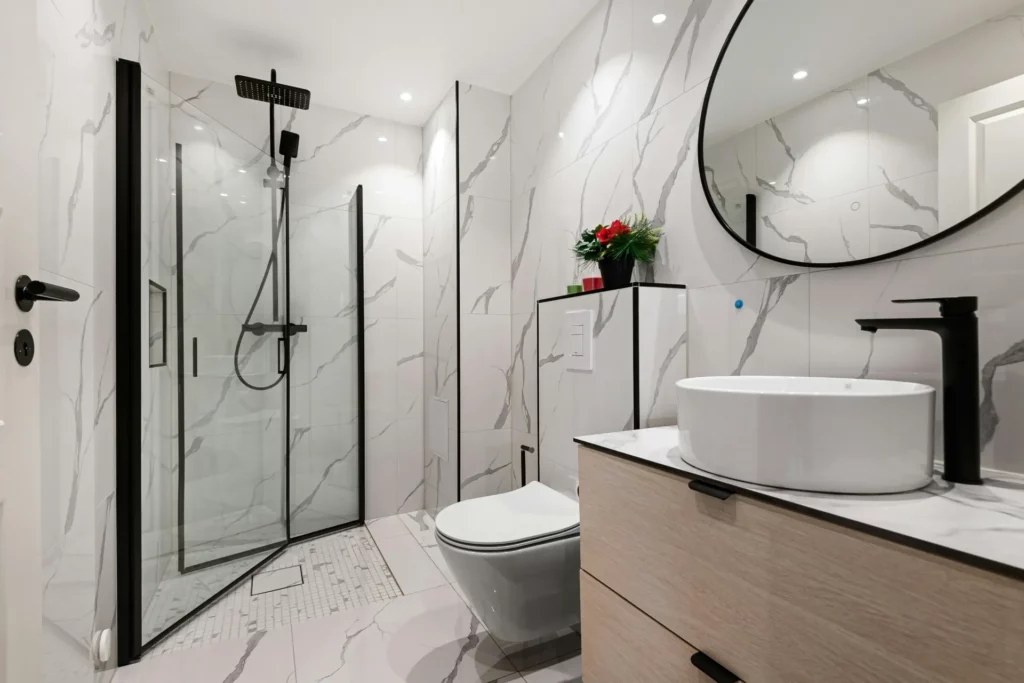 pexels-lisa-anna-901356985-19916721_optimized - RenovSmart Salle de bain moderne avec douche à l’italienne, carreaux effet marbre et robinetterie noire