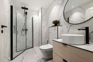 Salle de bain moderne avec douche à l’italienne, carreaux effet marbre et robinetterie noire
