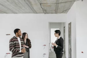 Un couple visite un bien immobilier en rénovation avec une conseillère.