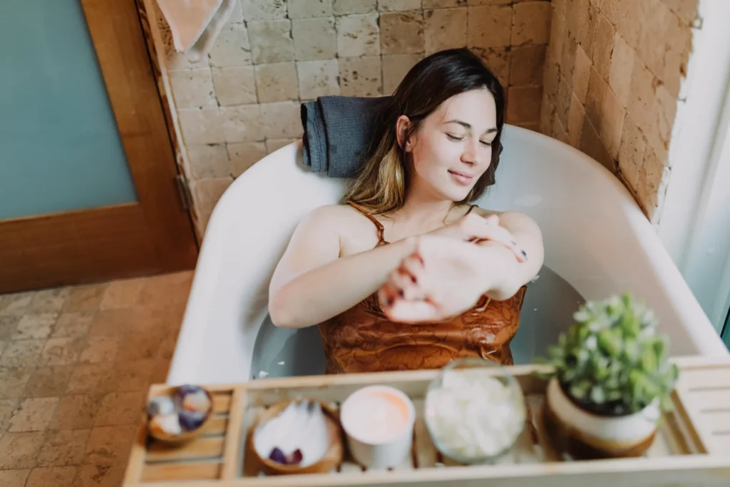 Femme détendue dans une baignoire avec accessoires de spa et plante décorative