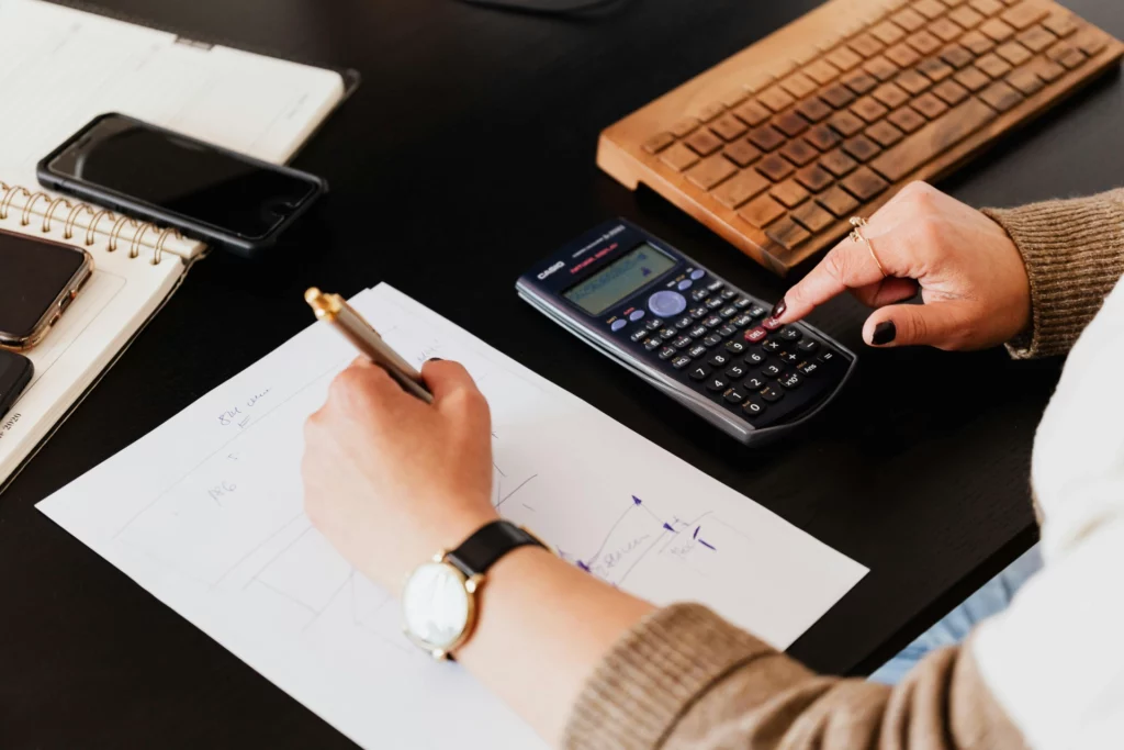 pexels-karolina-grabowska-4476375_optimized - RenovSmart Une personne utilise une calculatrice et écrit des notes sur un plan de travail.